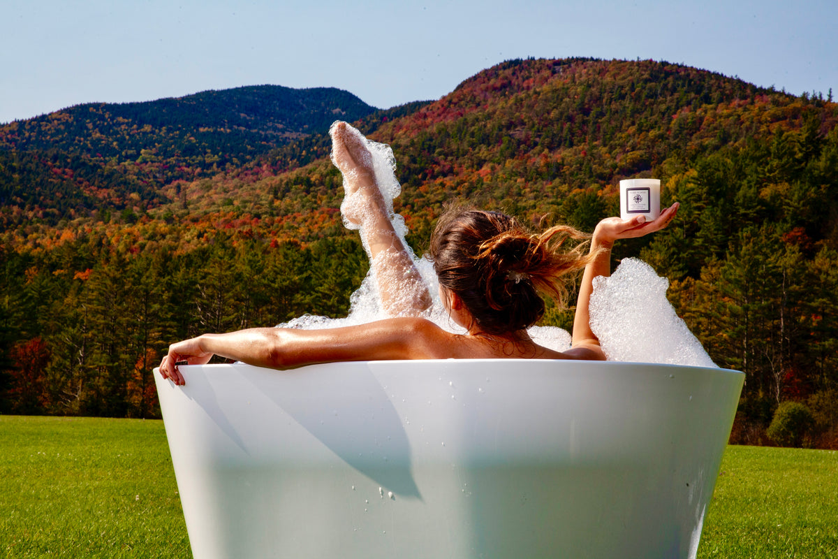 A woman relaxing in a soaking tub outdoors among autumn foliage