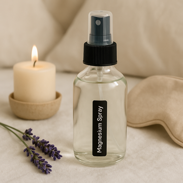 Clear spray bottle labeled 'Magnesium Spray' with lavender and a candle on a neutral background
